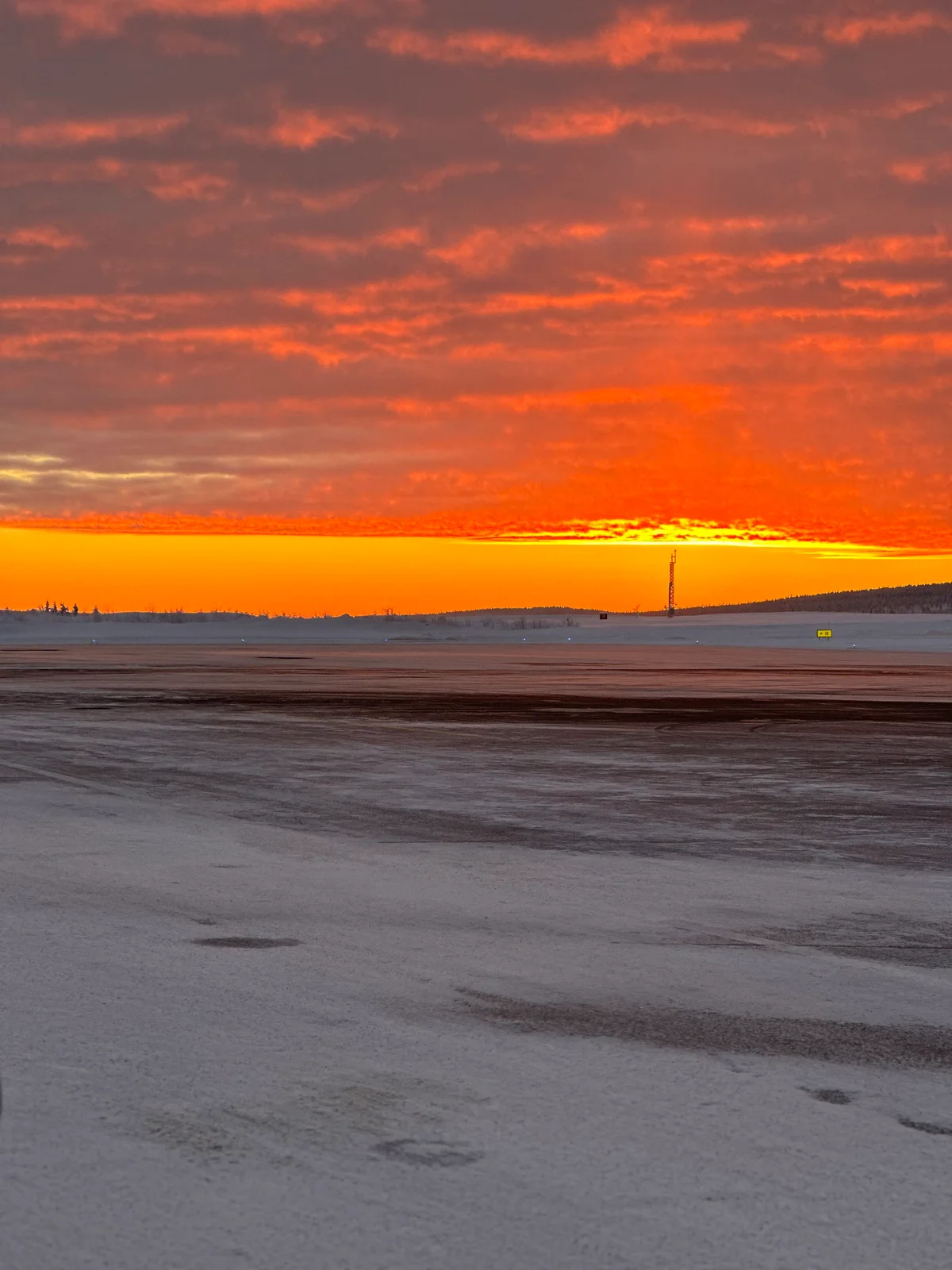 Ein glühender orange-roter Sonnenuntergang über einer weiten, verschneiten Ebene