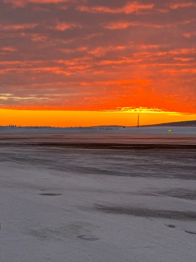 Ein glühender orange-roter Sonnenuntergang über einer weiten, verschneiten Ebene