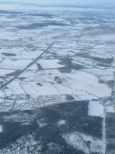 Verschneite Landschaft mit Feldern und Wäldern aus der Vogelperspektive