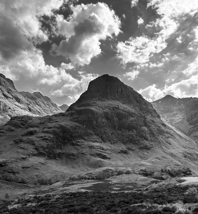 Der gleiche Berggipfel in Glen Coe als dramatische Schwarz-Weiß-Aufnahme unter Wolkenhimmel