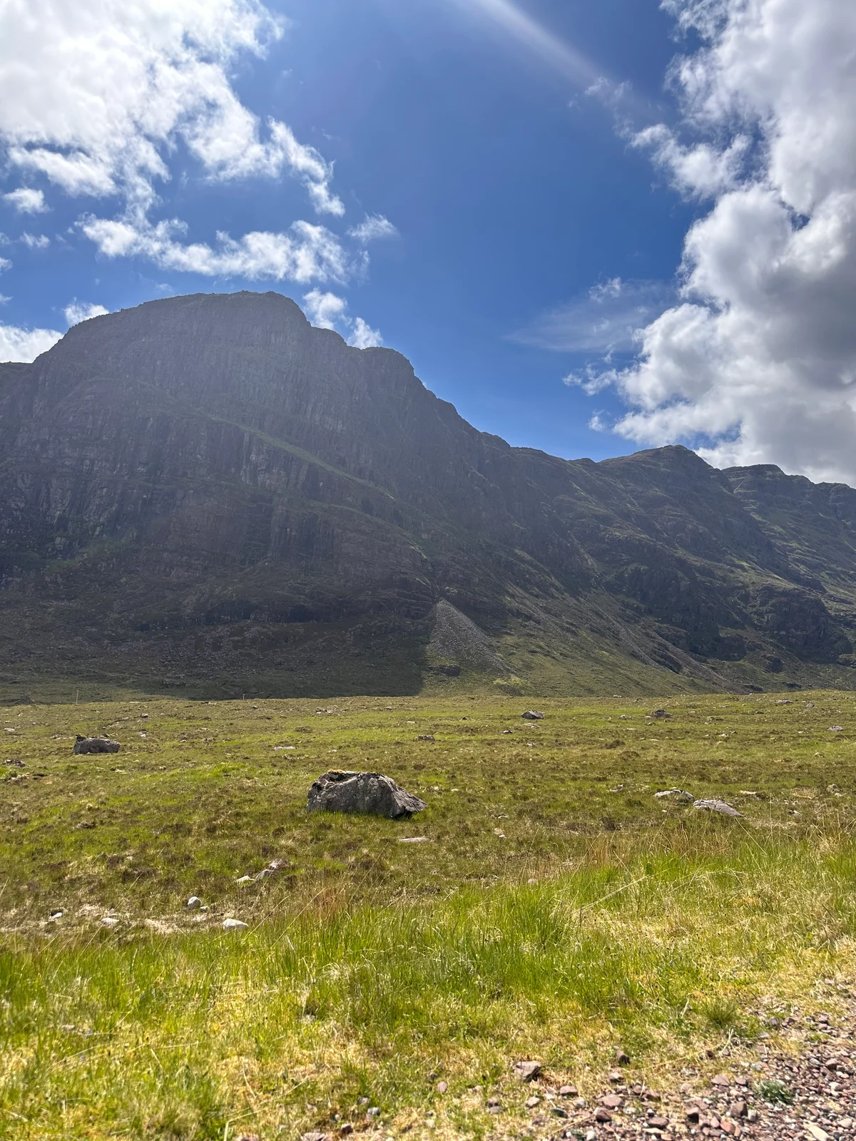 Eine dramatische grüne Felswand mit einem einzelnen Schaf in der schottischen Landschaft