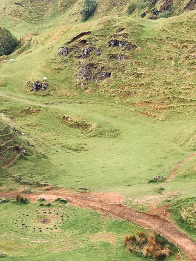 Blick von oben auf die Fairy Glen auf Skye mit Steinkreisen und gewellten grünen Hügeln