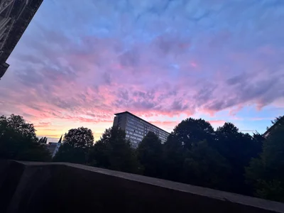 Rosa und violette Wolken über der Silhouette einer Stadt mit Bäumen in der Dämmerung