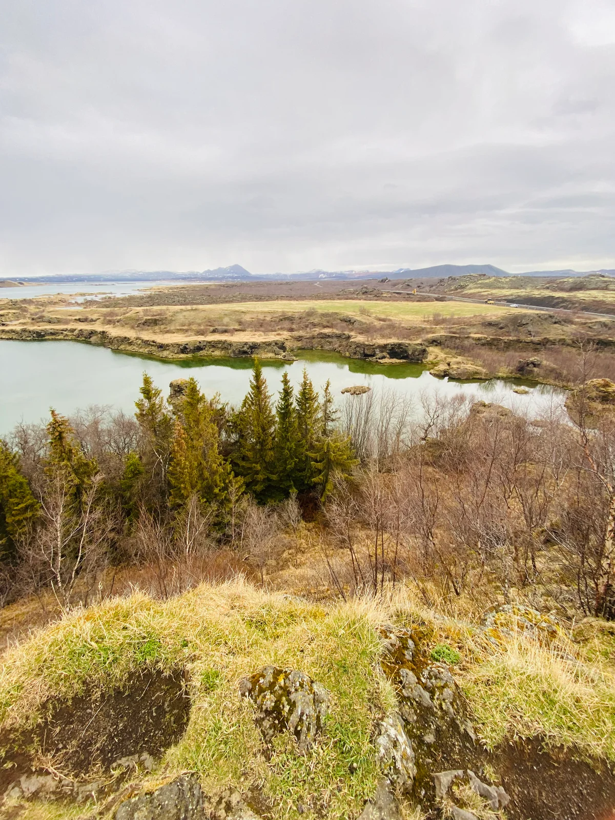 Blick über einen grünblauen See und karge Vegetation auf eine isländische Berglandschaft