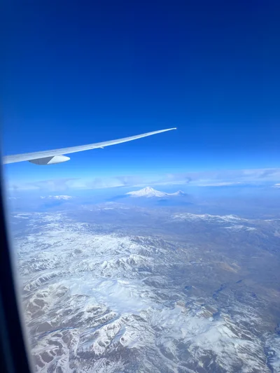 Flugzeugtragfläche über verschneiten Alpengipfeln unter tiefblauem Himmel